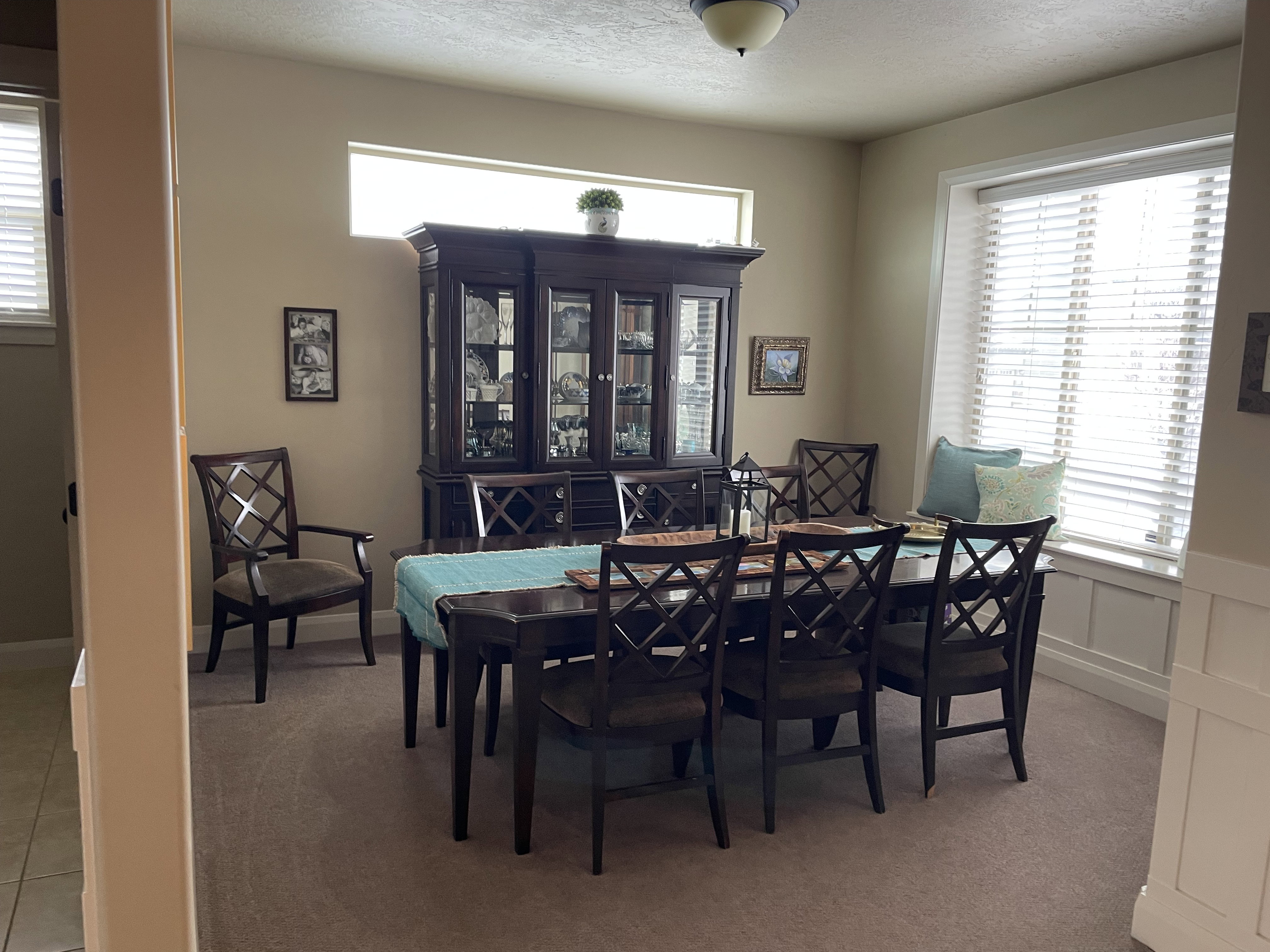 Dining area featuring a prominent window bench, neutral wall color, and carpeted flooring