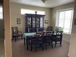 Dining area featuring a prominent window bench, neutral wall color, and carpeted flooring