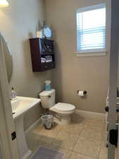 Pedestal sink with white basin, complemented by a wall-mounted dark wood-finish cabinet