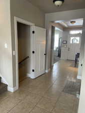 Foyer featuring neutral-toned tile flooring, white baseboards, and a paneled entry door with transom window