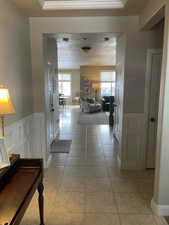 Spacious entryway featuring neutral-toned tile flooring, wainscoting, and crown molding