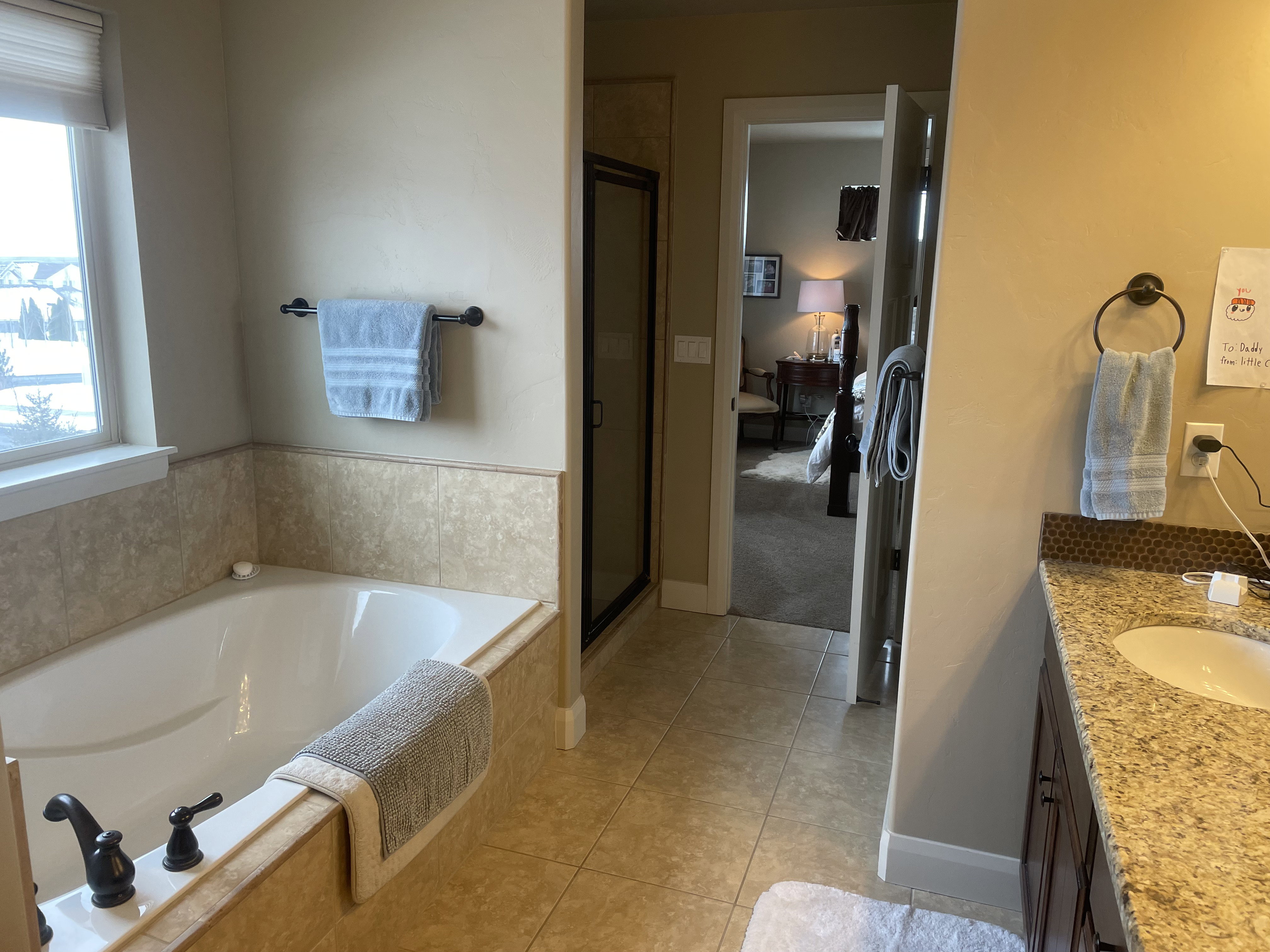 Bathroom featuring a built-in tub with dark bronze fixtures, tile surround, and a vanity with a granite countertop and integrated sink