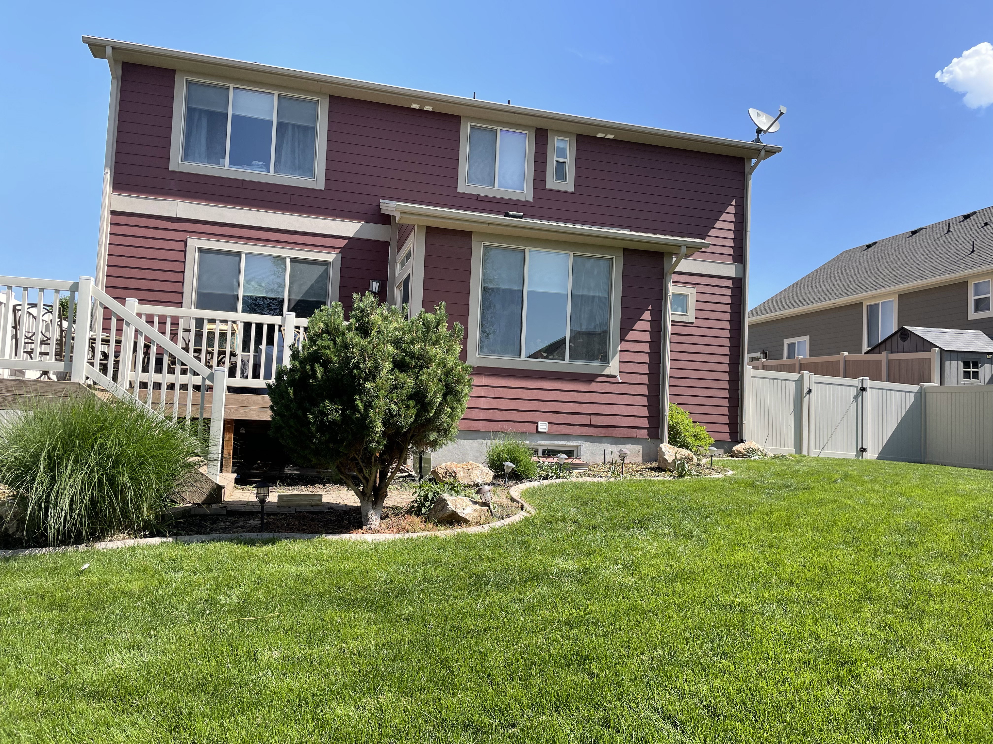 Expansive backyard featuring a manicured lawn, a multi-level deck with white railings, and a privacy fence