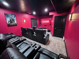 Dedicated media room featuring recessed lighting, wall-mounted sconces, and a large display screen
