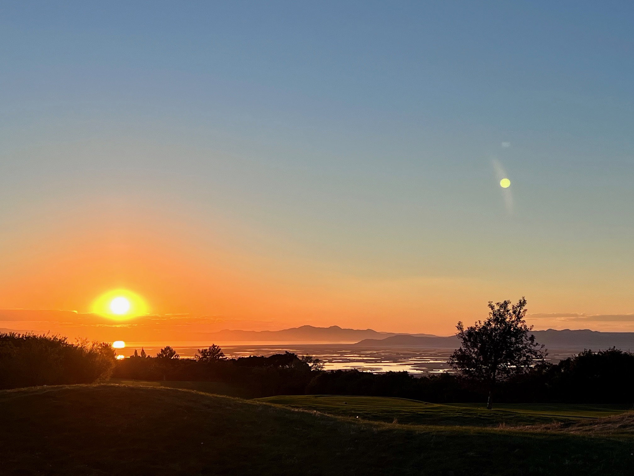 Expansive landscape featuring distant mountains and a body of water under a gradient sky