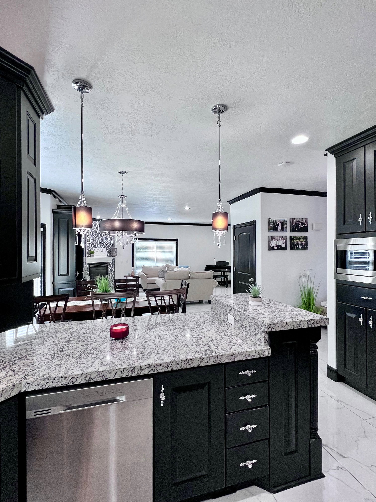 Kitchen island with granite countertops, black cabinetry, and pendant lighting