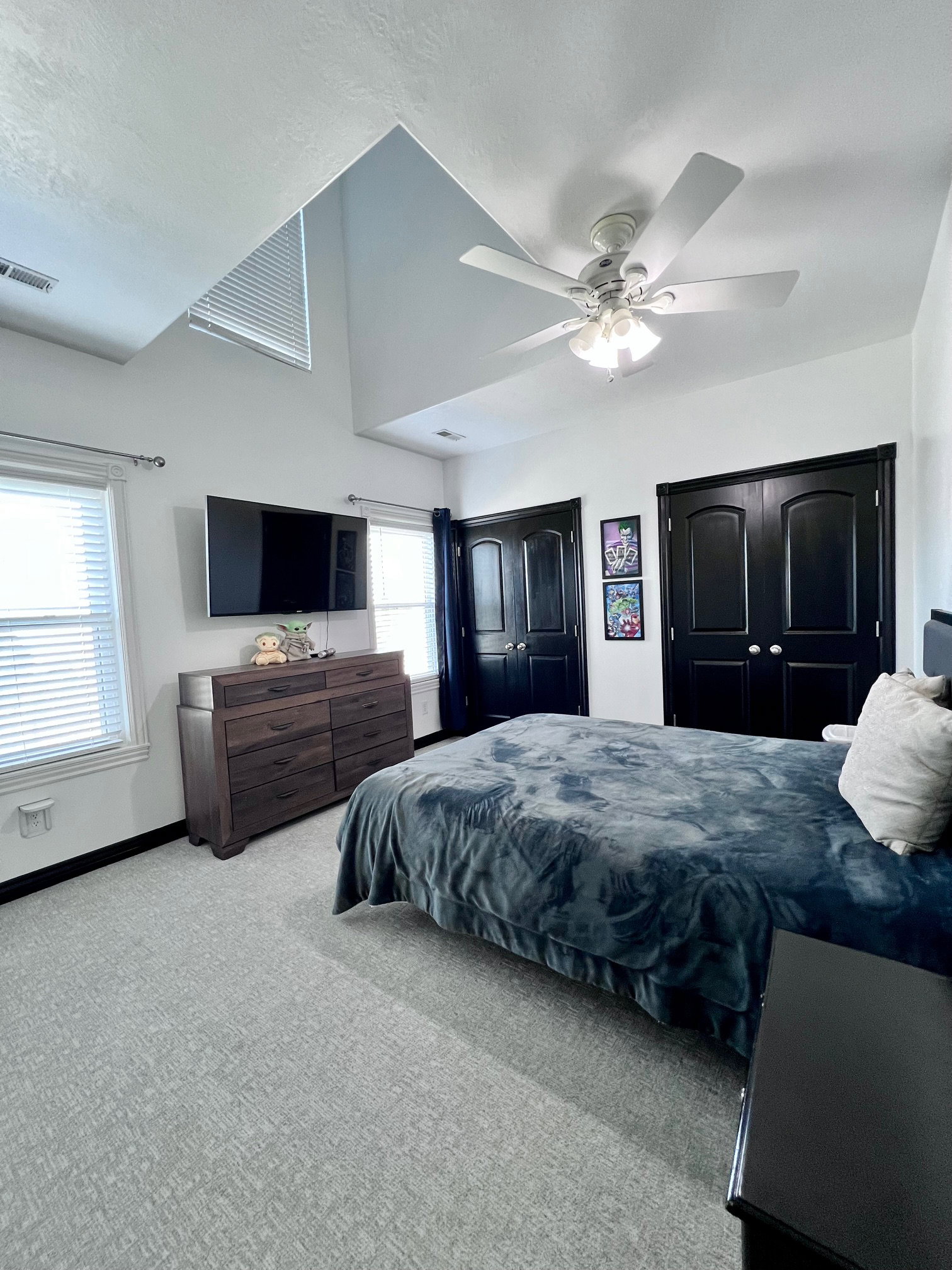 Vaulted ceilings with a ceiling fan, light gray patterned carpeting, black interior doors, and white window blinds
