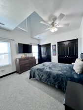 Vaulted ceilings with a ceiling fan, light gray patterned carpeting, black interior doors, and white window blinds