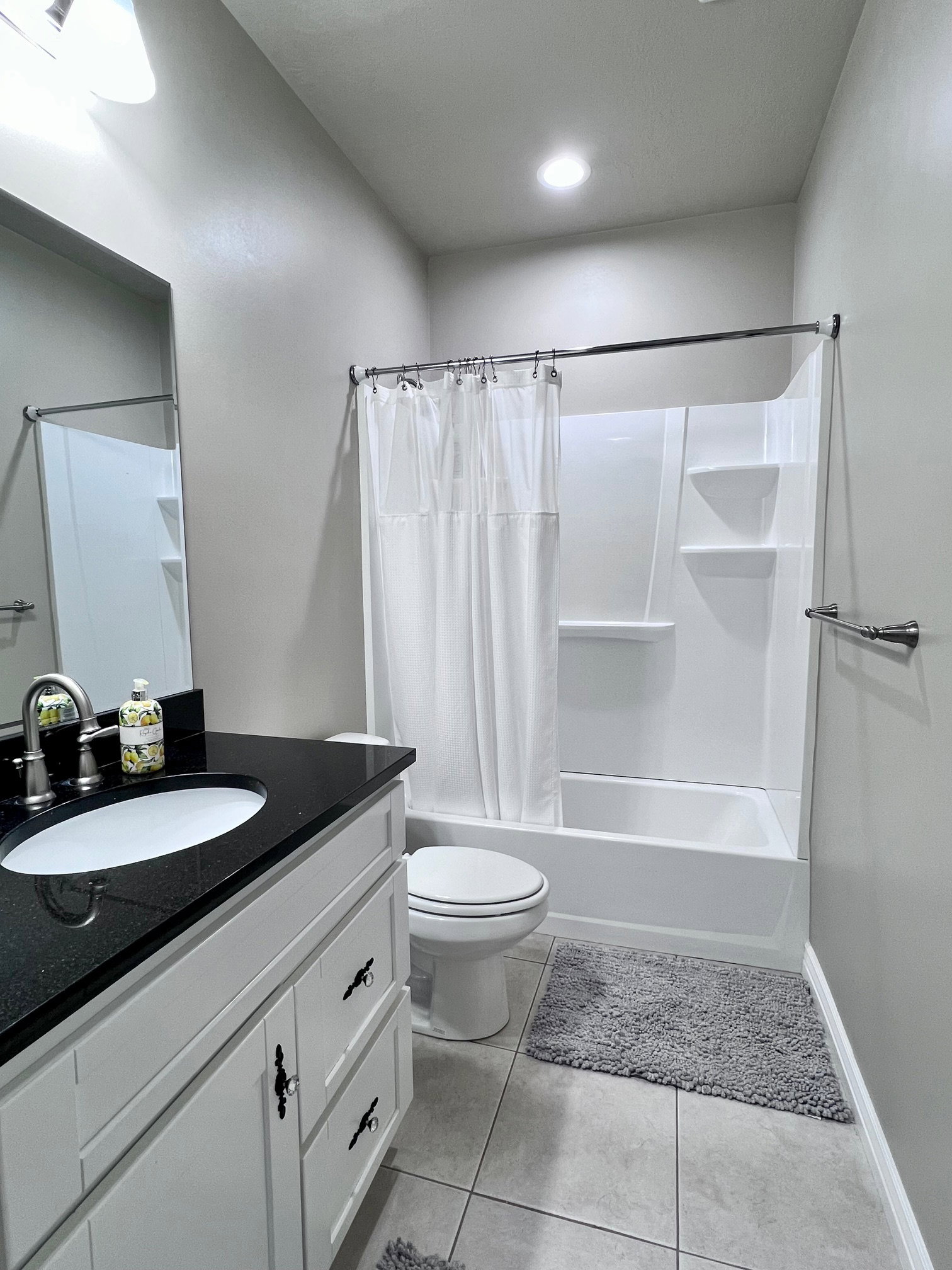 Bathroom featuring a white vanity with black countertop, undermount sink, and brushed nickel faucet