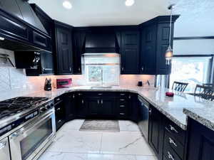 U-shaped kitchen featuring black cabinetry with decorative hardware, light granite countertops, and a white subway tile backsplash