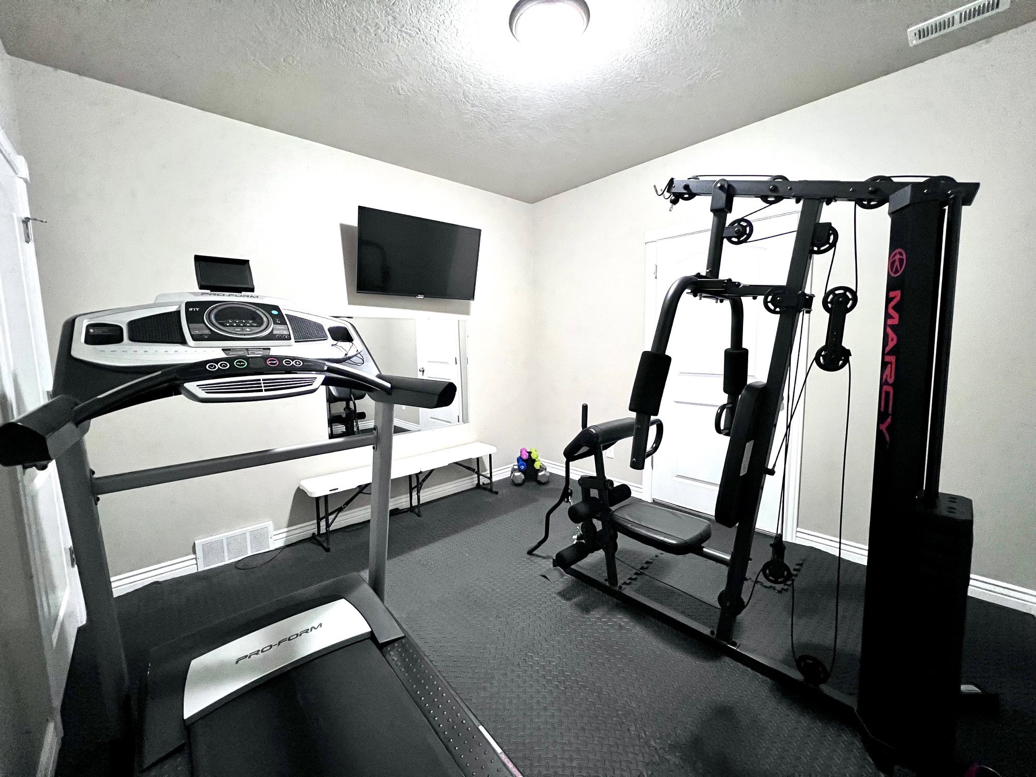 Dedicated room featuring textured walls, a ceiling-mounted light fixture, and dark interlocking floor tiles
