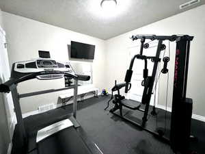 Dedicated room featuring textured walls, a ceiling-mounted light fixture, and dark interlocking floor tiles