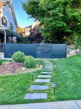 Modern privacy fence with integrated gate, bordered by a stone paver walkway and a manicured lawn