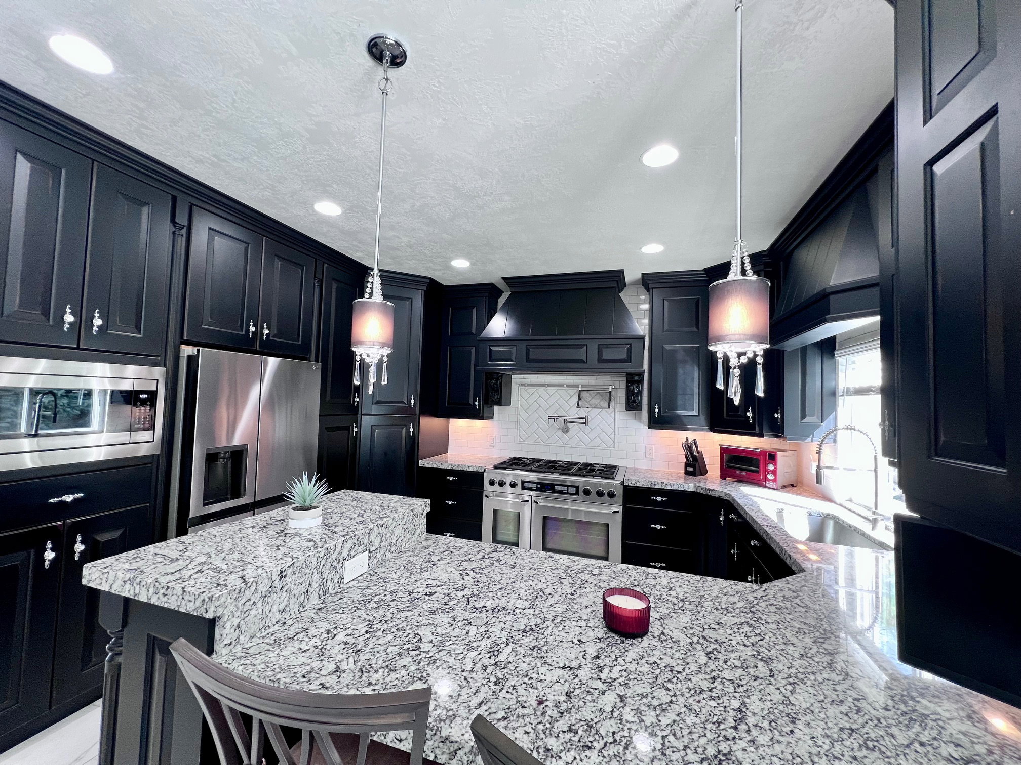 Kitchen featuring dark cabinetry, stainless steel appliances, speckled stone countertops, a tile backsplash, and recessed lighting