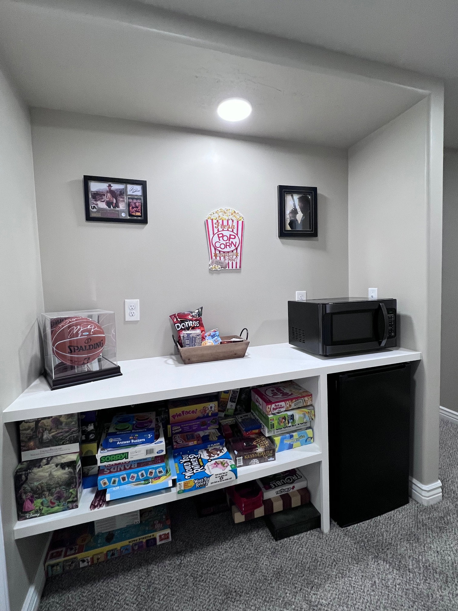 Recessed alcove with built-in white shelving, integrated lighting, and carpeted flooring