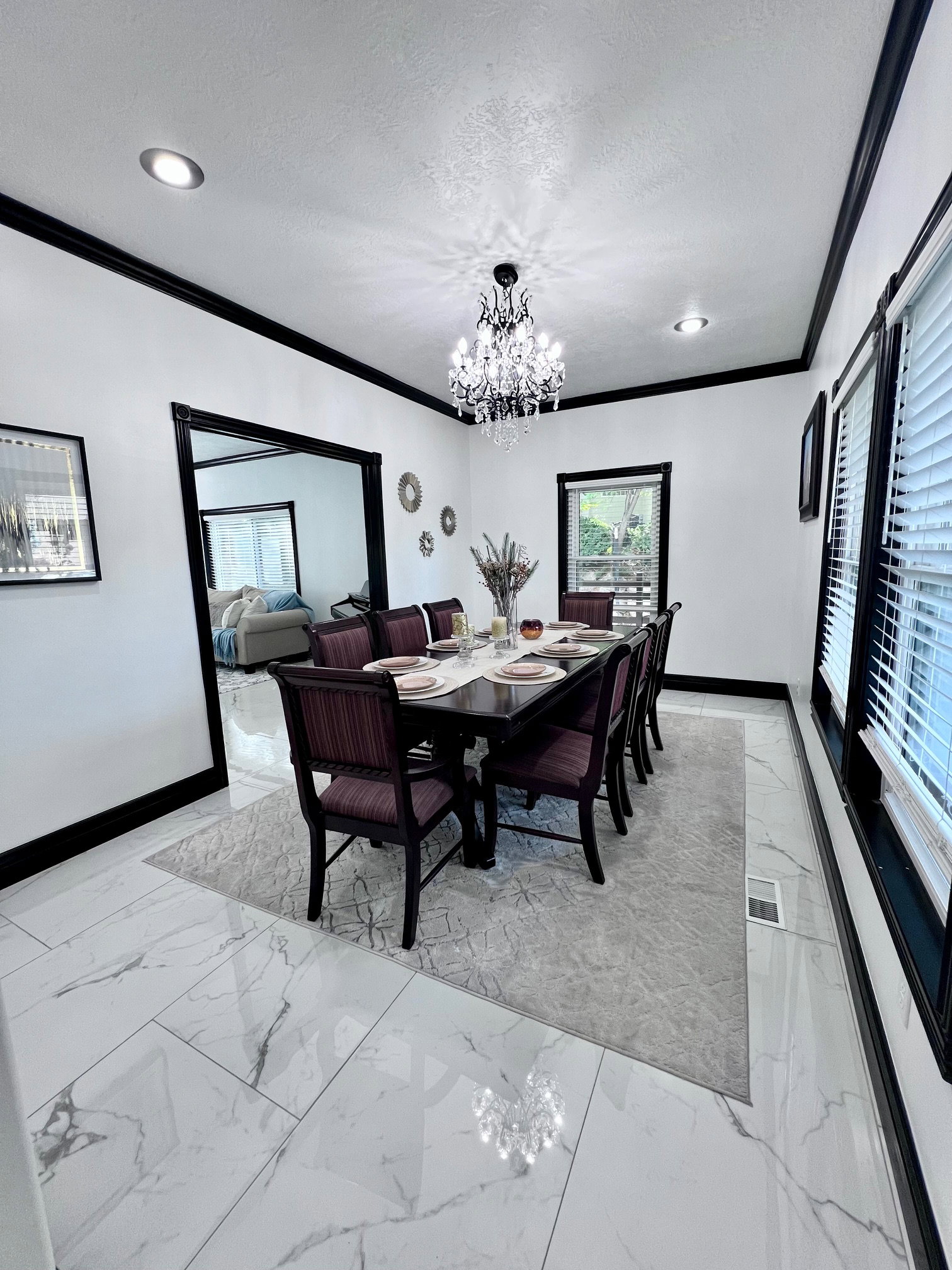Dining area featuring white marble-look tile flooring, black crown molding, and a crystal chandelier