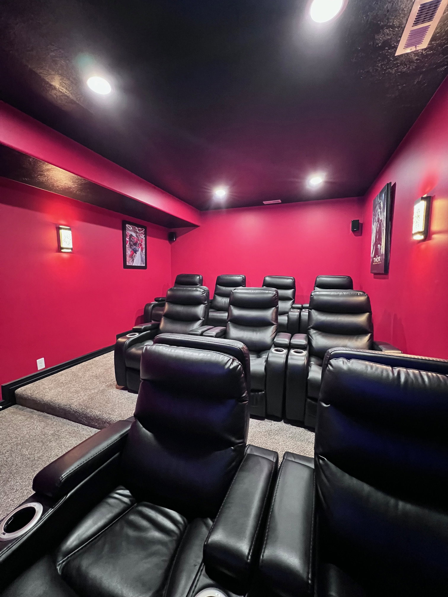 Dedicated home theater featuring tiered seating, recessed ceiling lighting, and wall sconces