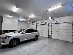 Spacious garage featuring two overhead doors with automatic openers, a durable epoxy-coated concrete floor, and multiple fluorescent ceiling light fixtures