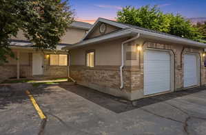 Exterior featuring a two-car garage with white paneled doors, brick facade detailing, and stucco siding