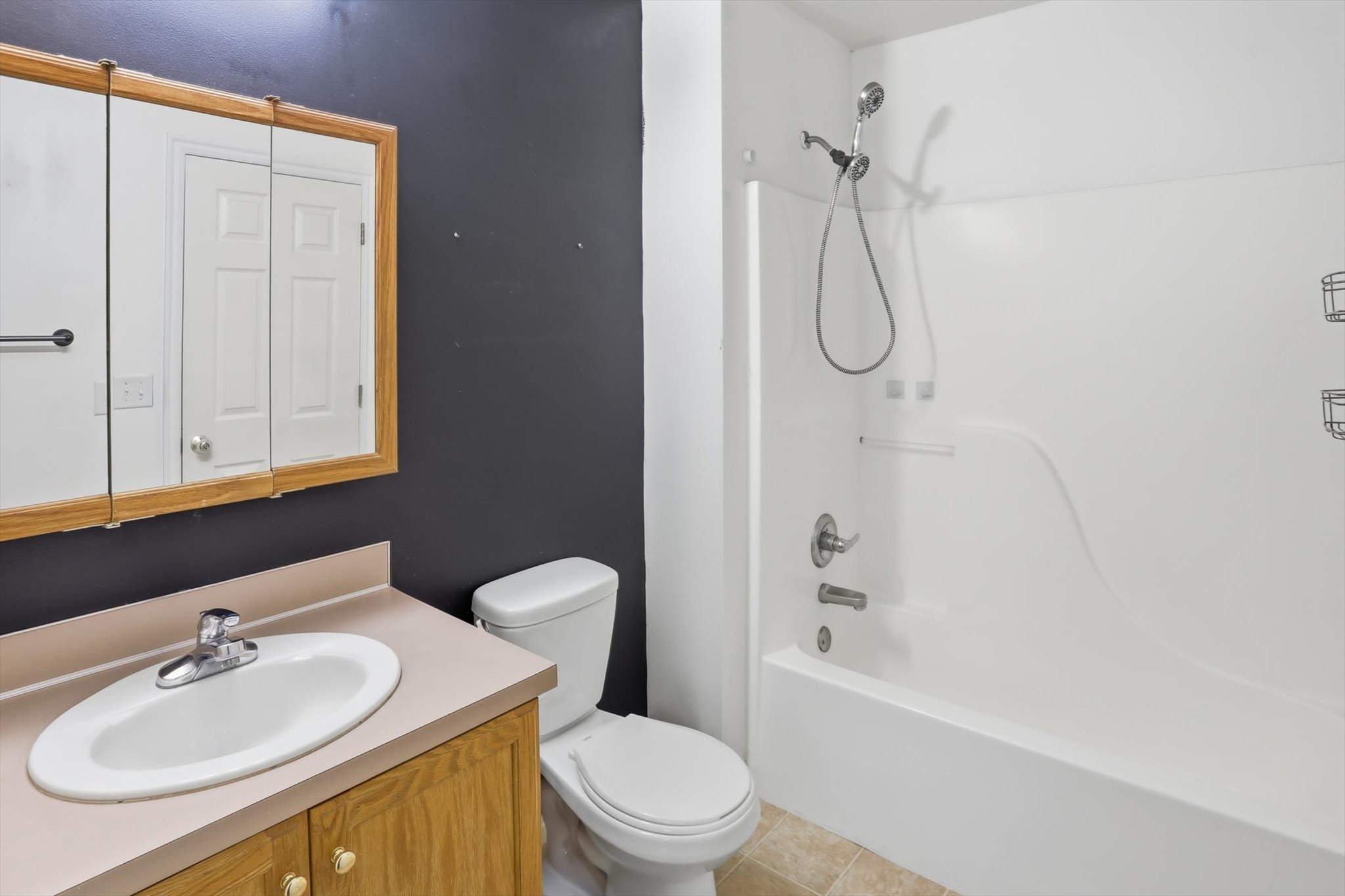 Bathroom featuring a vanity with wood-finish cabinetry, a white oval sink, and a light-toned countertop