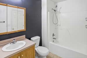 Bathroom featuring a vanity with wood-finish cabinetry, a white oval sink, and a light-toned countertop