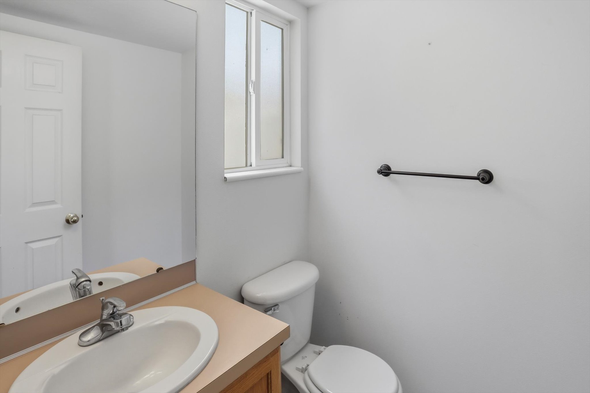 1/2 Bath featuring a wood vanity with a light-toned countertop, an undermount sink, and a chrome faucet