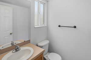 1/2 Bath featuring a wood vanity with a light-toned countertop, an undermount sink, and a chrome faucet