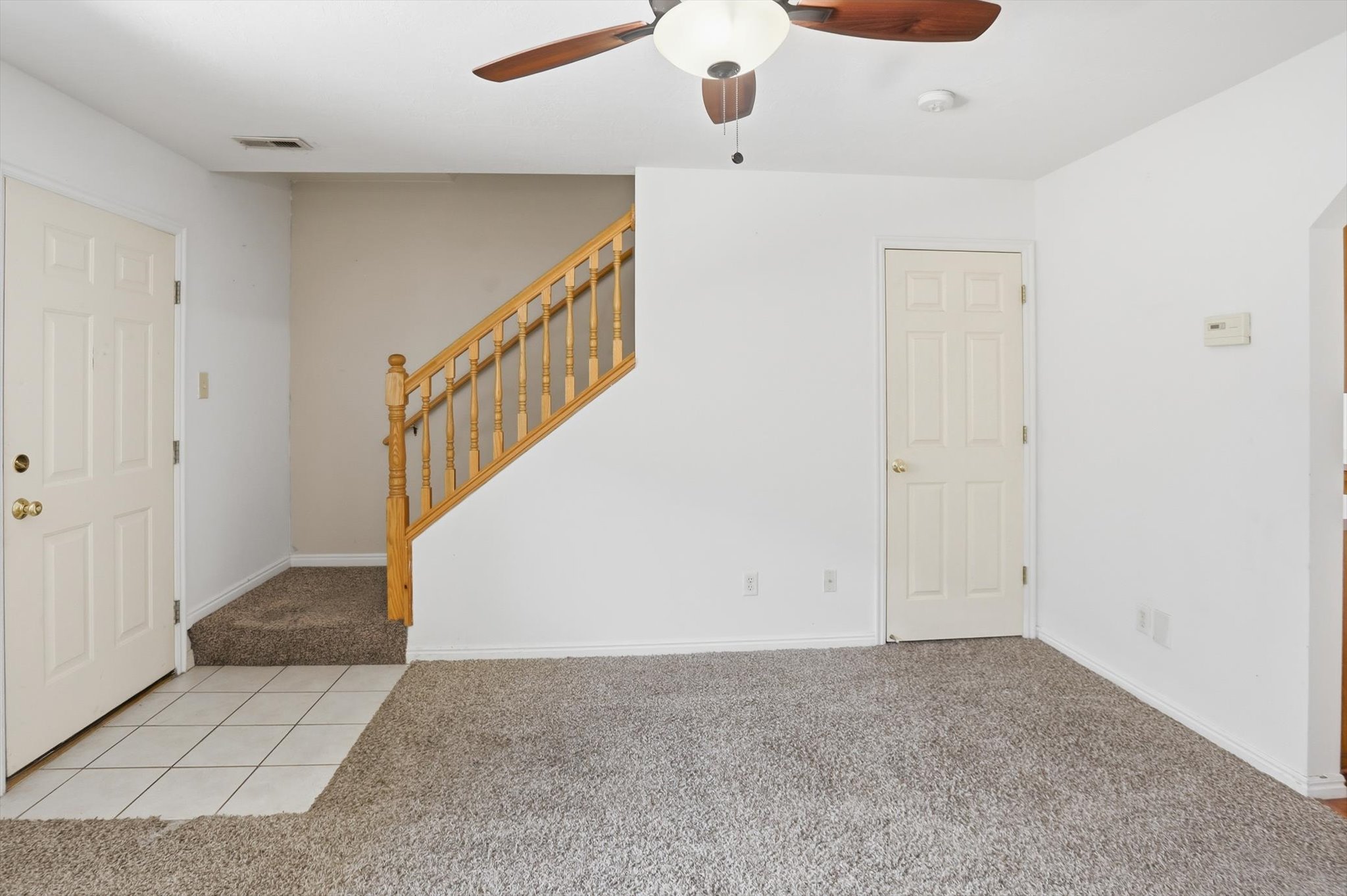 Foyer entry with tile flooring leading to a carpeted living space