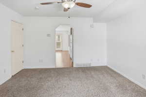 Carpeted living area with white walls and a ceiling fan
