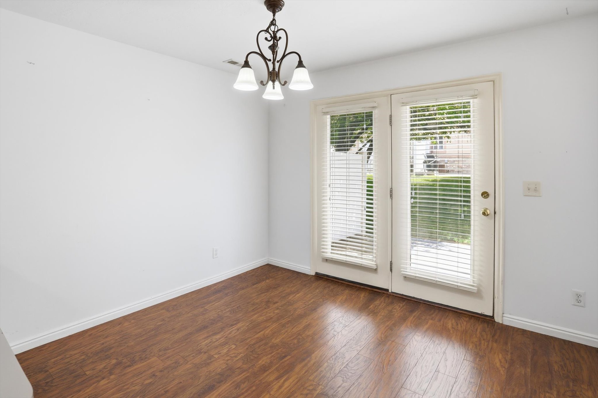 Wood-finish flooring throughout, featuring a double French door entry with integrated blinds