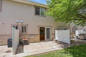 Rear exterior with a concrete patio, sliding glass door entry, and partial privacy fencing