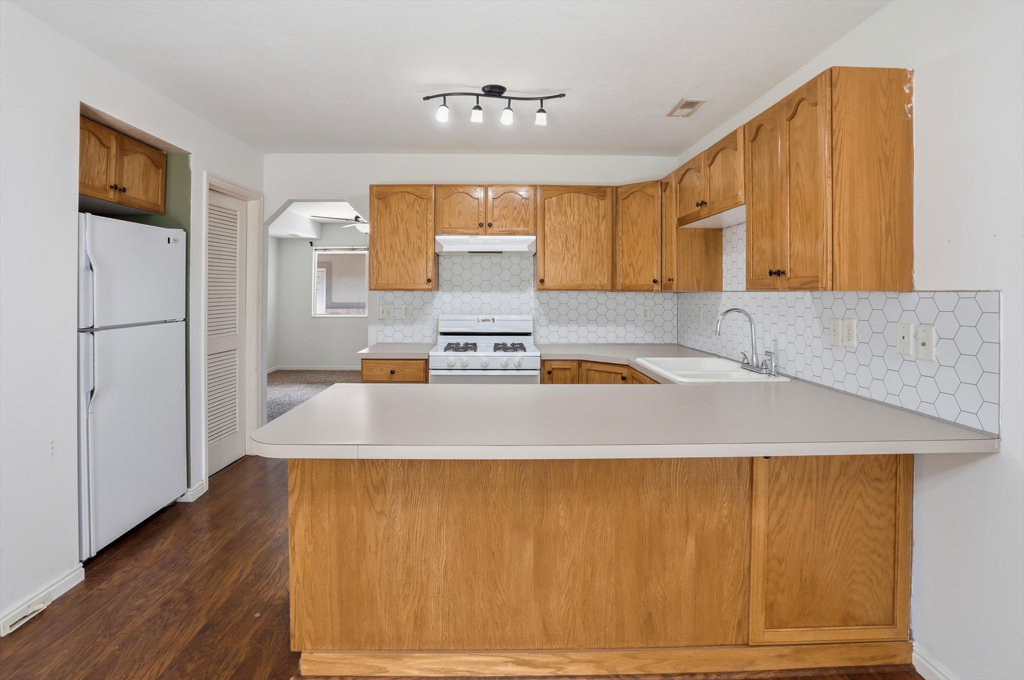 Kitchen featuring wood-finish cabinetry, white countertops, and hexagonal tile backsplash