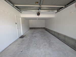 Extra deep garage featuring a concrete floor, painted walls, and an overhead garage door mechanism