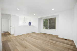 Spacious room featuring wood-finish flooring, recessed lighting, and a large window