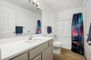 Bathroom featuring a single vanity with an integrated sink, quartz countertop, and matching tan cabinetry