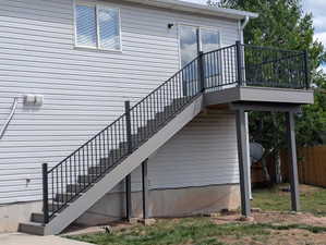 Composite deck with black metal railings, 4 foot wide stairs providing outdoor access from the upper level