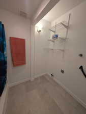Dedicated laundry area featuring wire shelving, wall sconce lighting, and wood-finish flooring