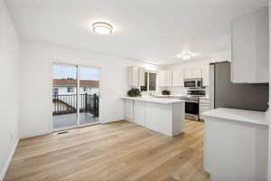 Open-concept living area featuring light wood-finish flooring, white walls, and recessed lighting