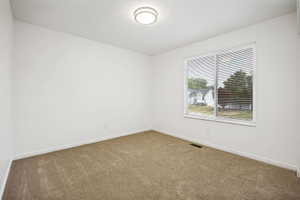 Front upstairs bedroom with double closet and sliding doors. Neutral-toned carpeting complements bright white walls and trim