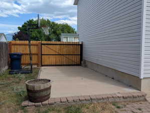 RV parking area featuring concrete surfacing, a brick-lined edge, and wooden privacy fencing with gate.