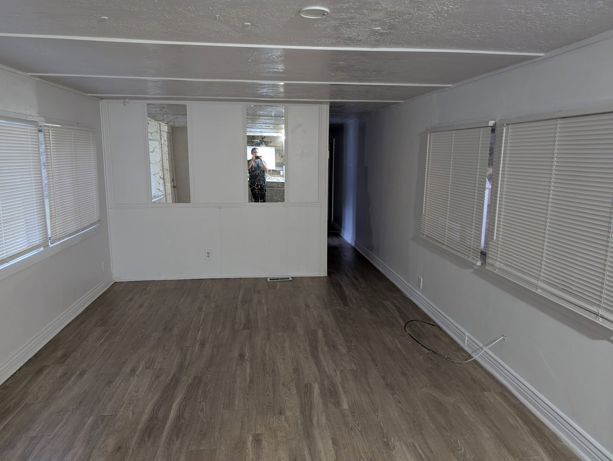 Spacious room featuring wood-finish flooring, white baseboards, and multiple windows with blinds