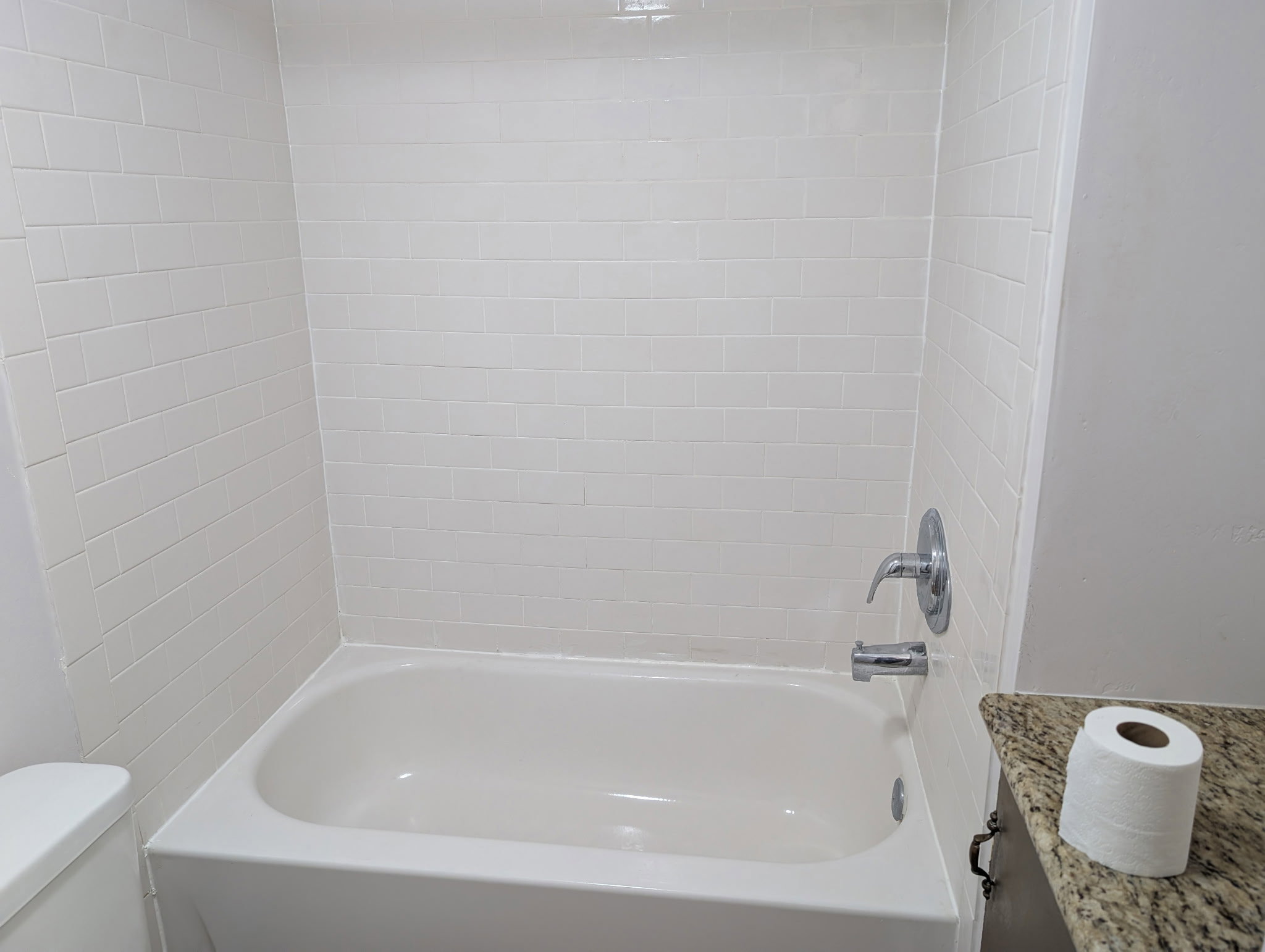 White subway tile shower surround with a white bathtub
