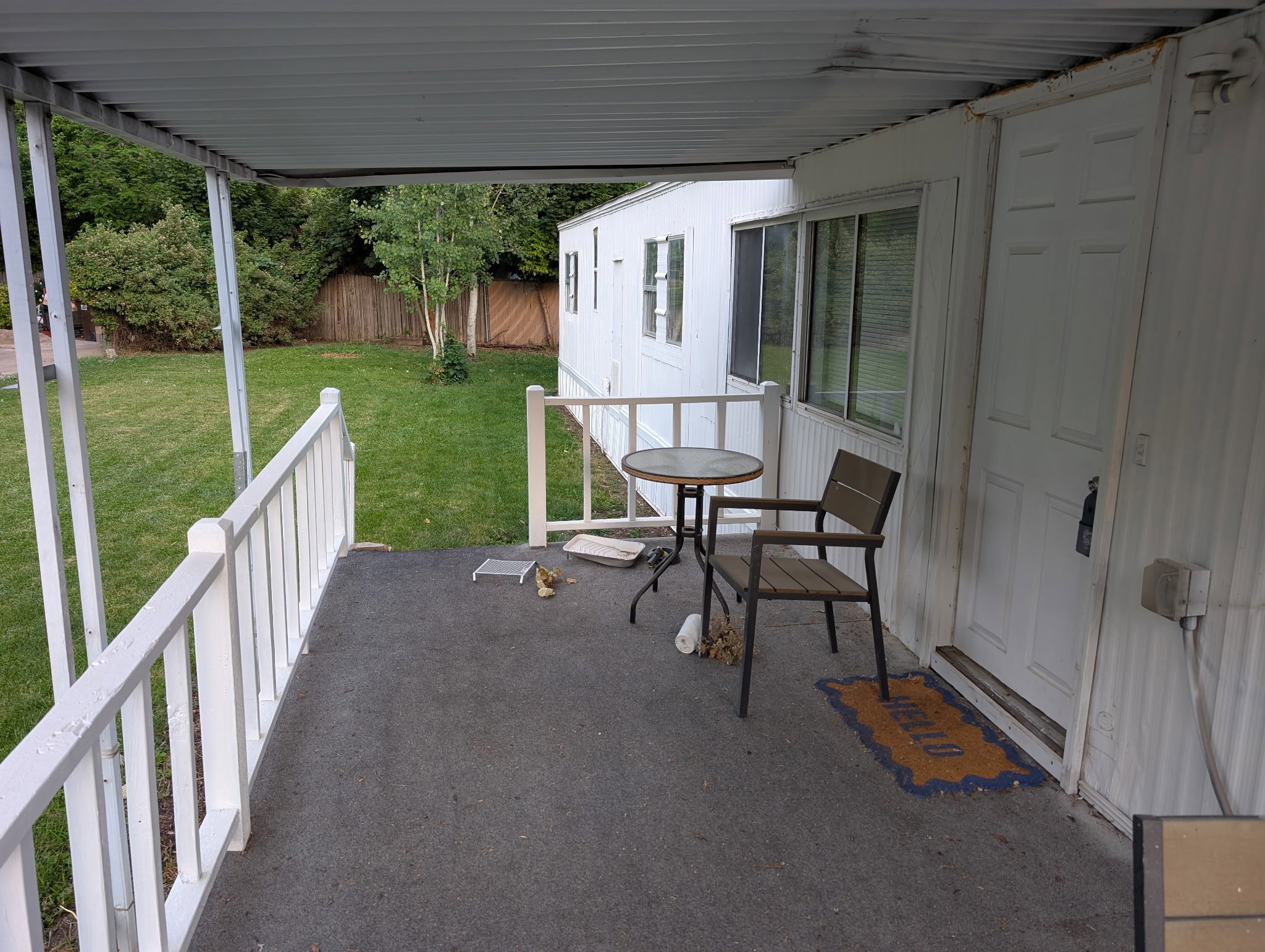 Covered porch with white railings, a white paneled door, and multiple windows