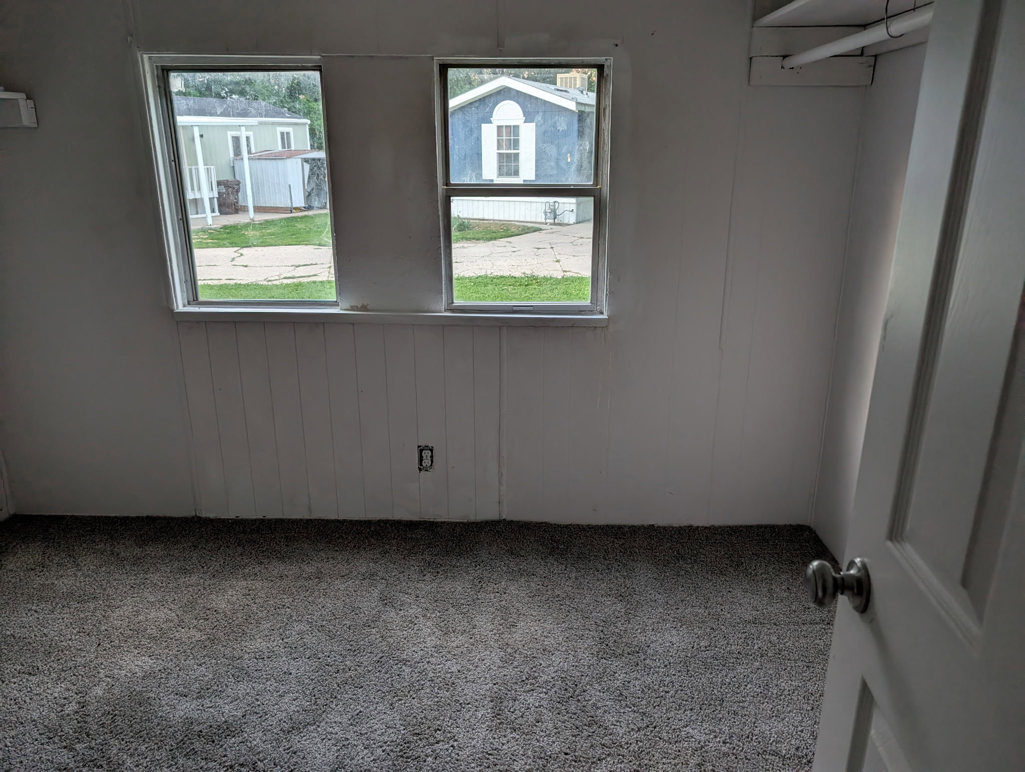 Interior room featuring two windows, light-colored walls, and gray carpet flooring