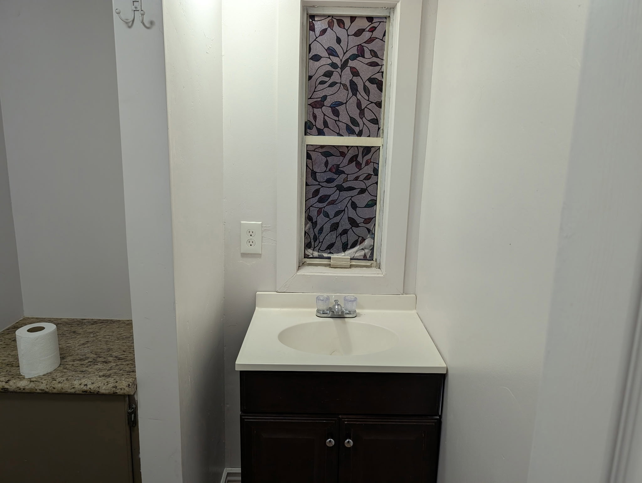 Bathroom vanity featuring a white countertop with an integrated sink and a dark wood-finish cabinet
