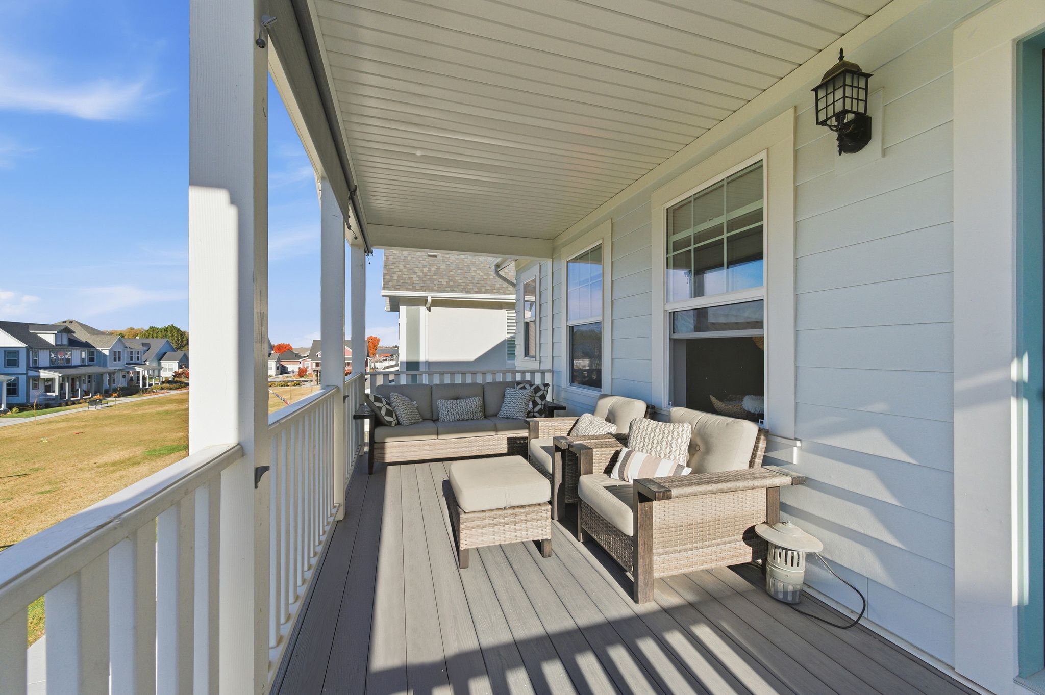 Inviting covered porch featuring composite decking, white architectural columns, and a coordinating painted railing