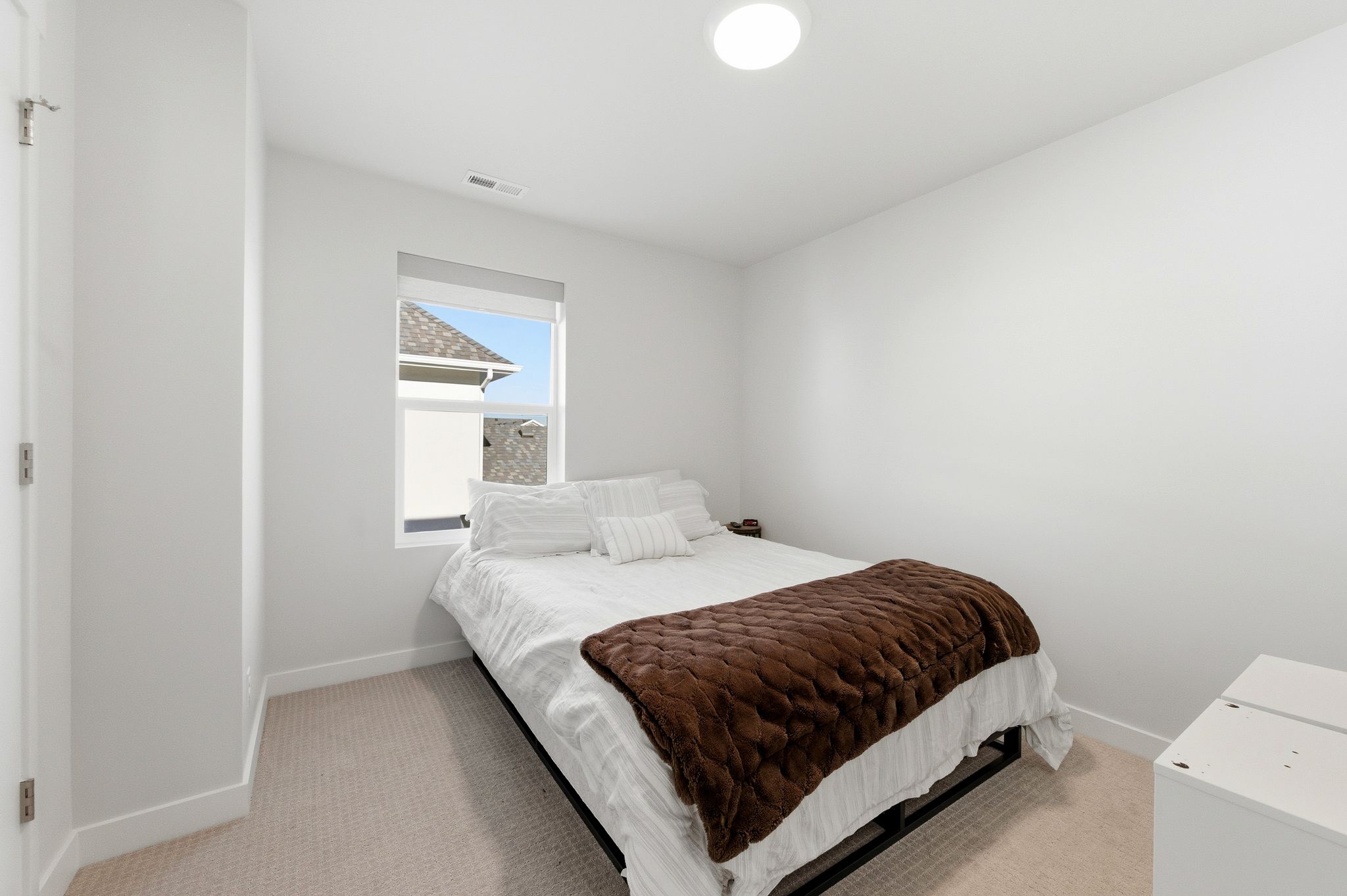 Carpeted room with a window, white walls, and a flush-mount ceiling light fixture