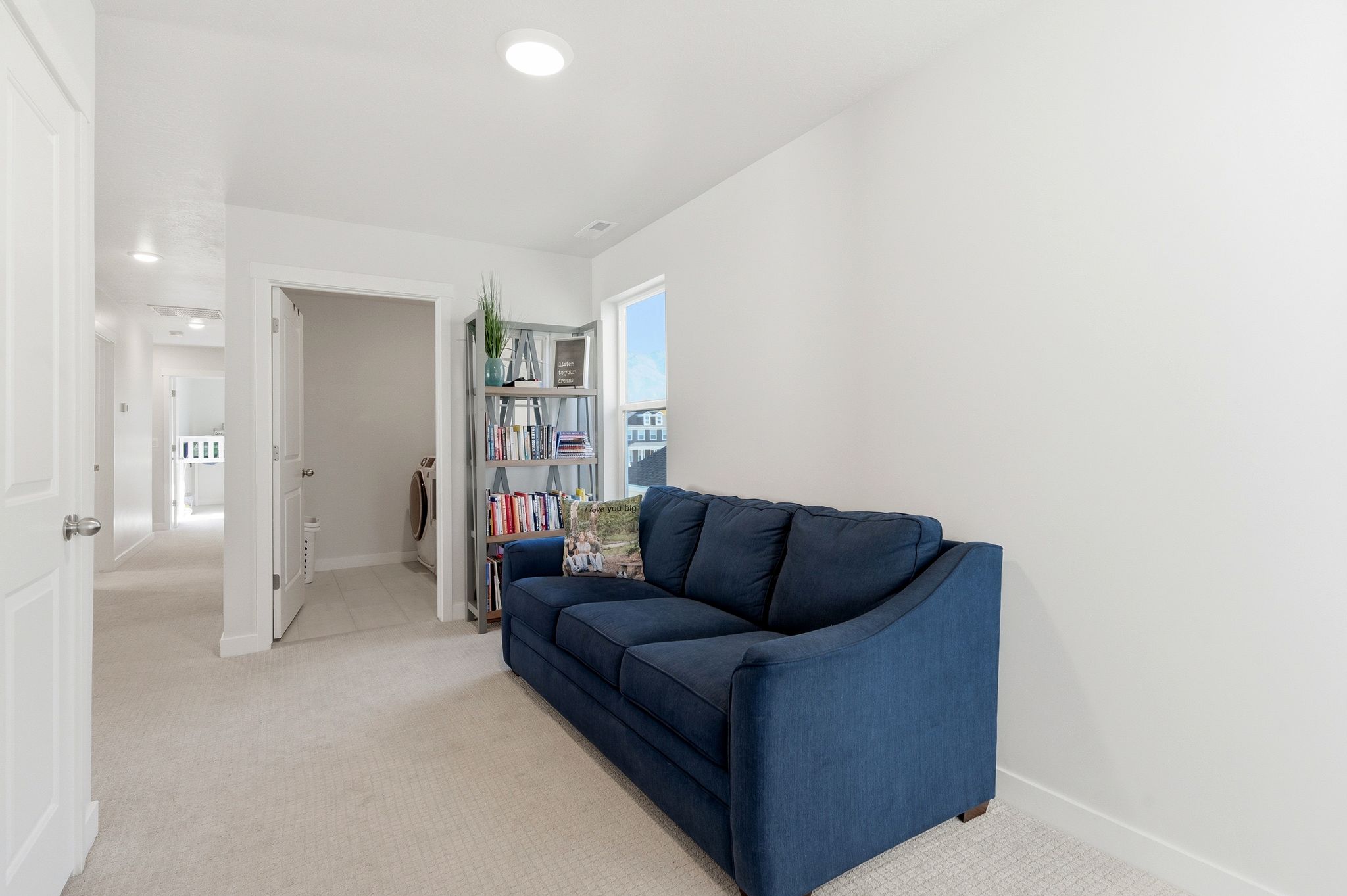 Carpeted hallway featuring recessed lighting and a laundry area with tile flooring and a built-in shelf