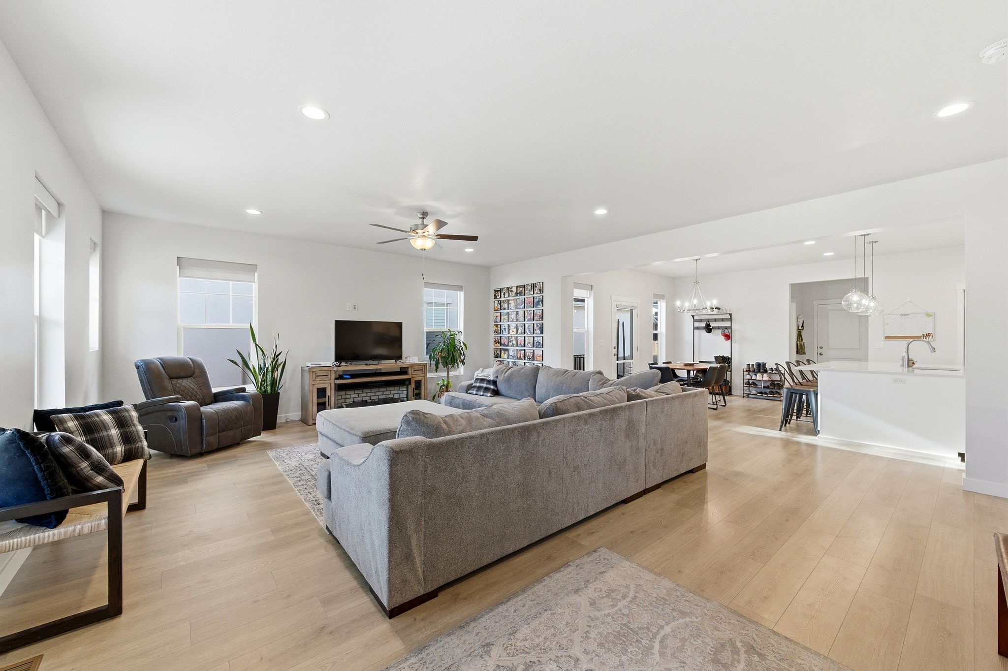 Spacious open-concept living area featuring light wood-finish flooring, recessed lighting, and a ceiling fan