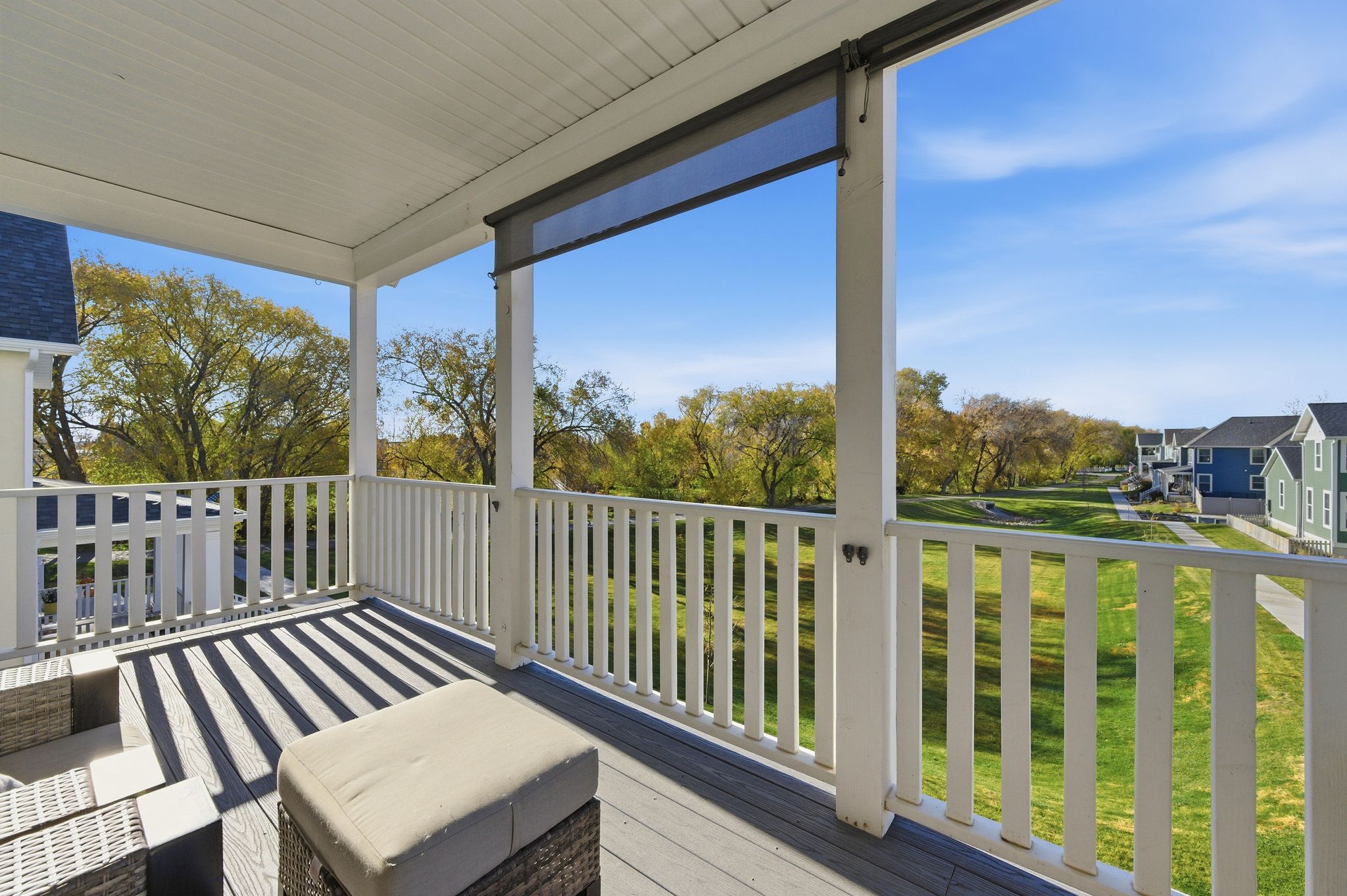 Covered outdoor balcony featuring composite decking, white railing, and a retractable shade